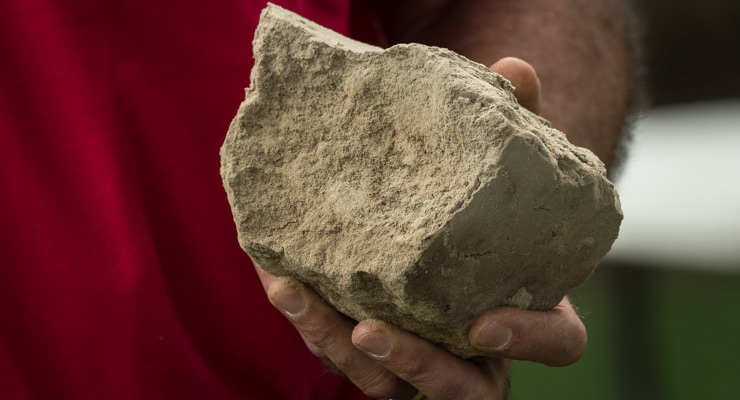 "Photo of someone holding a large chunk of dry, compacted soil"