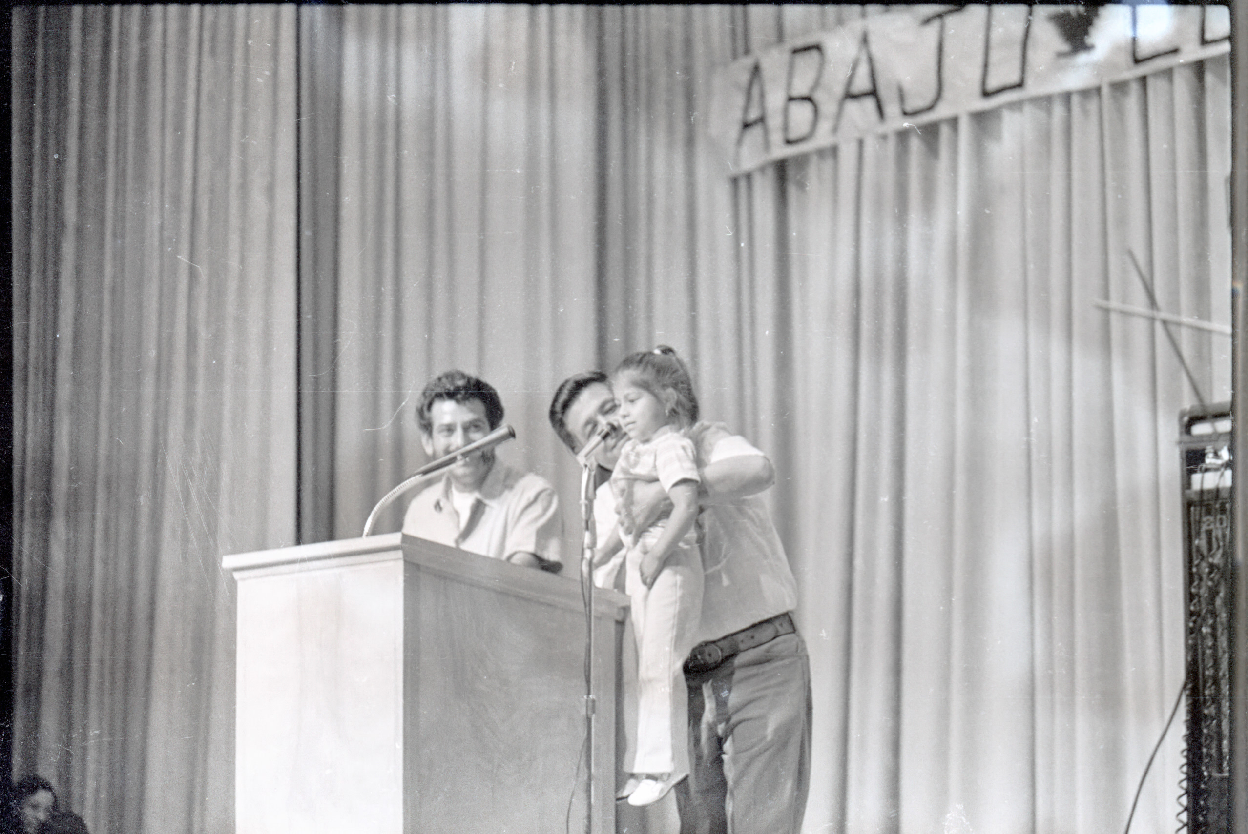 Three people standing at a podium in front of microphones