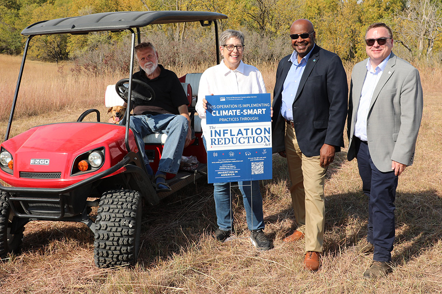 Four people standing next to a motorized cart