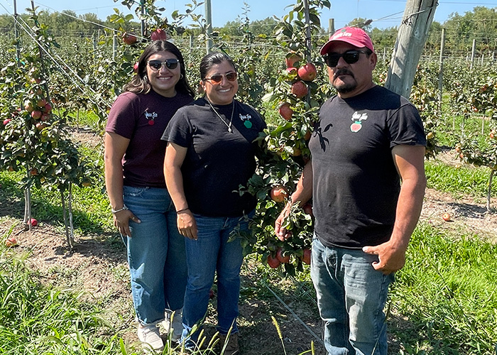 Three people standing next to and apple tree