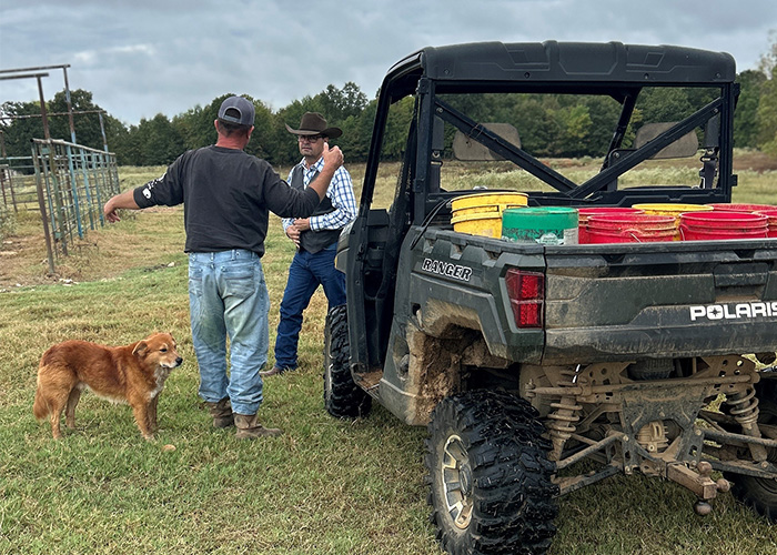 Two people and a dog standing next to a motorized cart