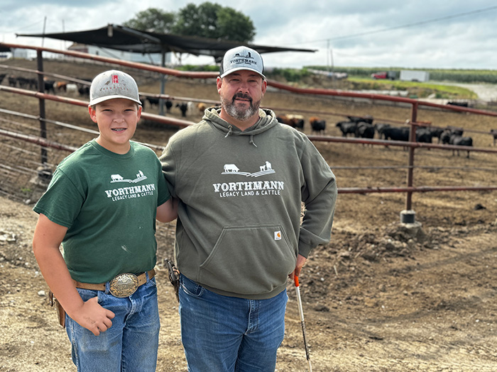 Two people standing by fence with cows in background