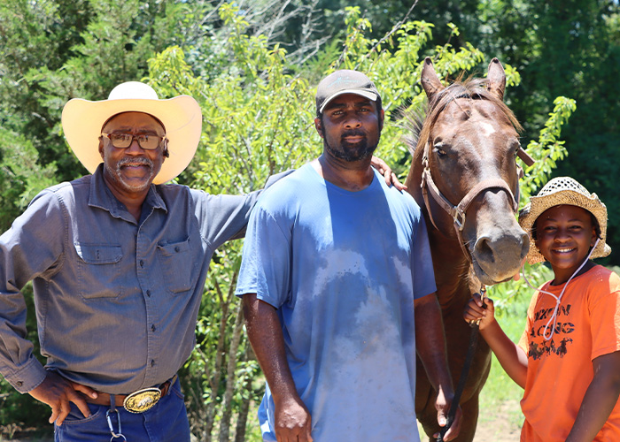 Three people standing next to a horse