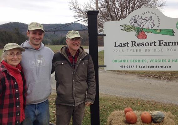 Eugenie Doyle (left) and Sam Burr (right) with their son Silas (center) beside their Last Resort Farm sign