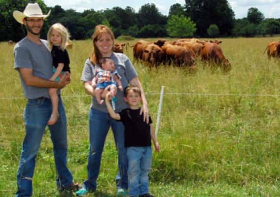 Family stands in front of their cattle