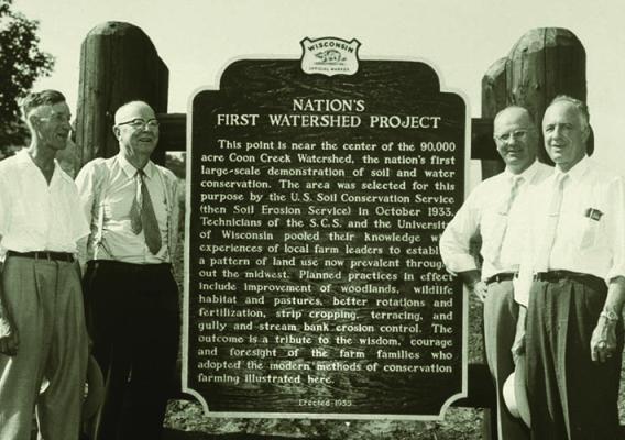 Dr. Hugh Hammond Bennett (second from left), first Chief of the former Soil Conservation Service, stands with former SCS officials next to a watershed project historical marker commemorating the nation’s first large-scale soil and water conservation project in Coon Valley, Wisconsin. 