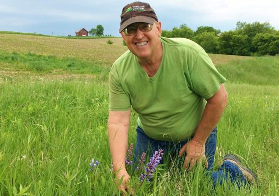 Dale Bigler kneeling in field smiling at camera