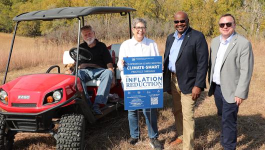 Four people standing next to a motorized cart