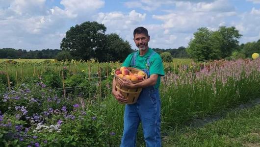 Person standing in a field holding a pumpkin